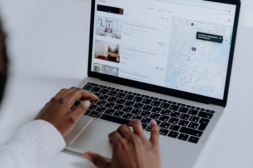 Mastering the First Impression: Your intriguing post title goes here Hands typing on laptop searching Airbnb for accommodation options with map view.